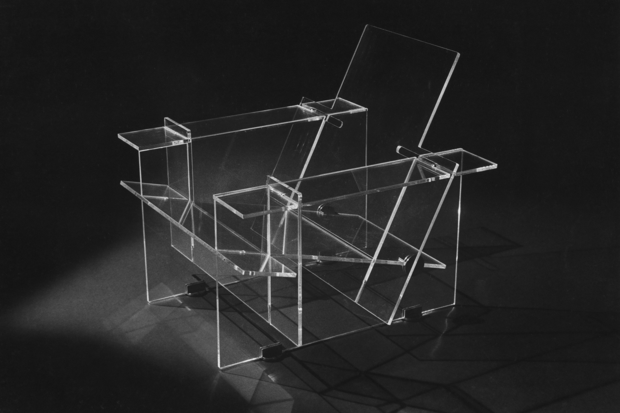 Clear fabricated acrylic components arranged against a dark background, showing polished edges, formed panels and assembly details.