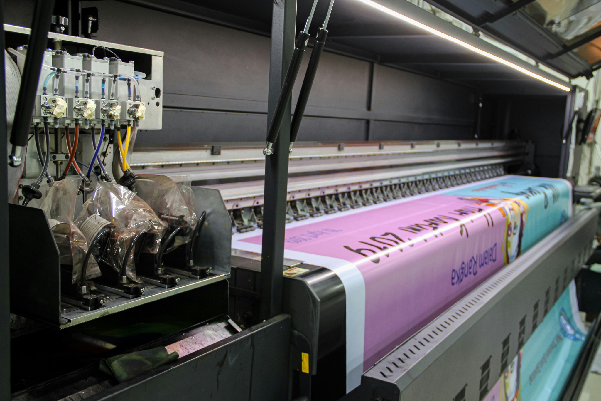 Wide-format digital print production equipment with material loaded, showing a production-stage view of large-format printing.