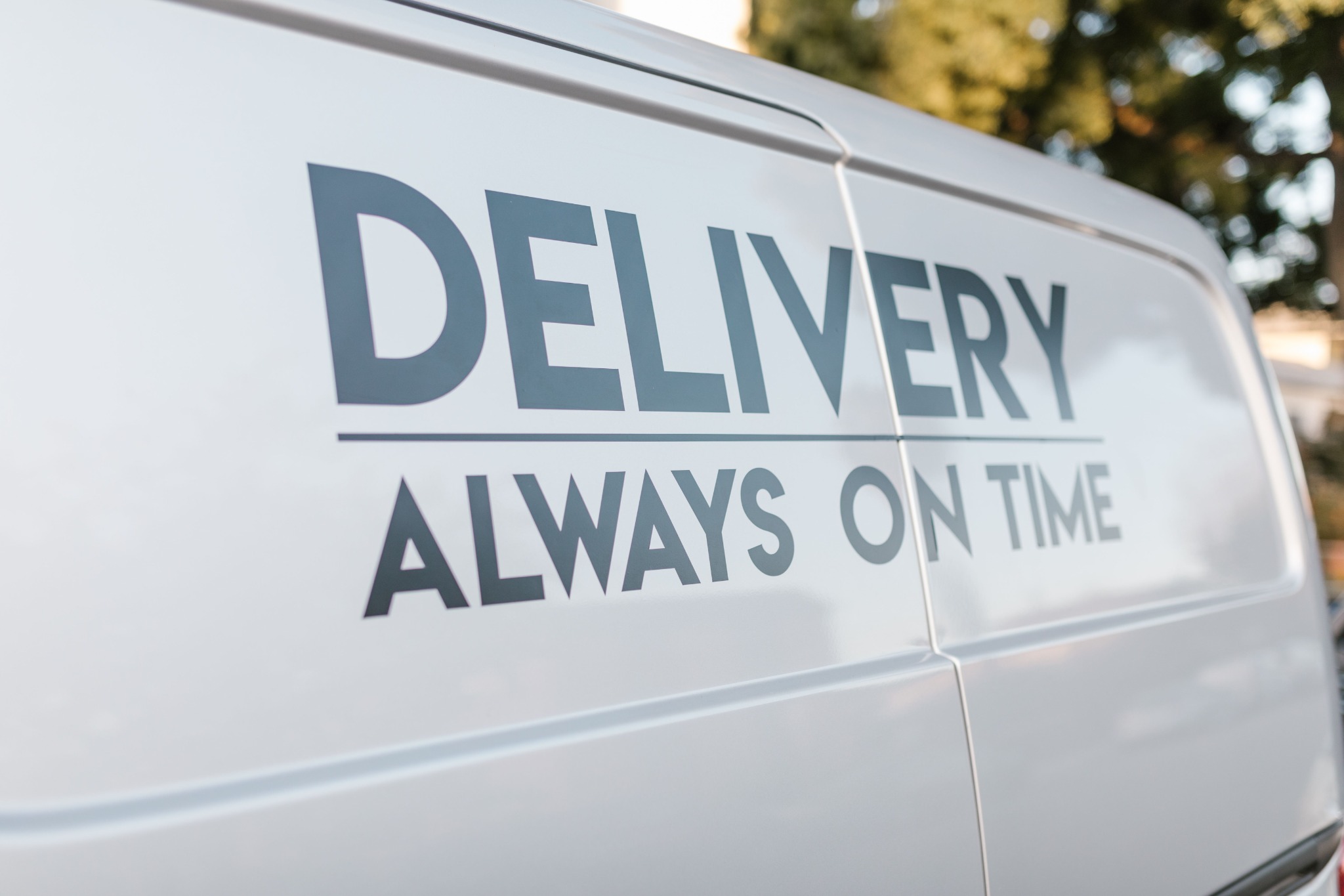 A white delivery van with large applied lettering, demonstrating commercial vehicle branding.