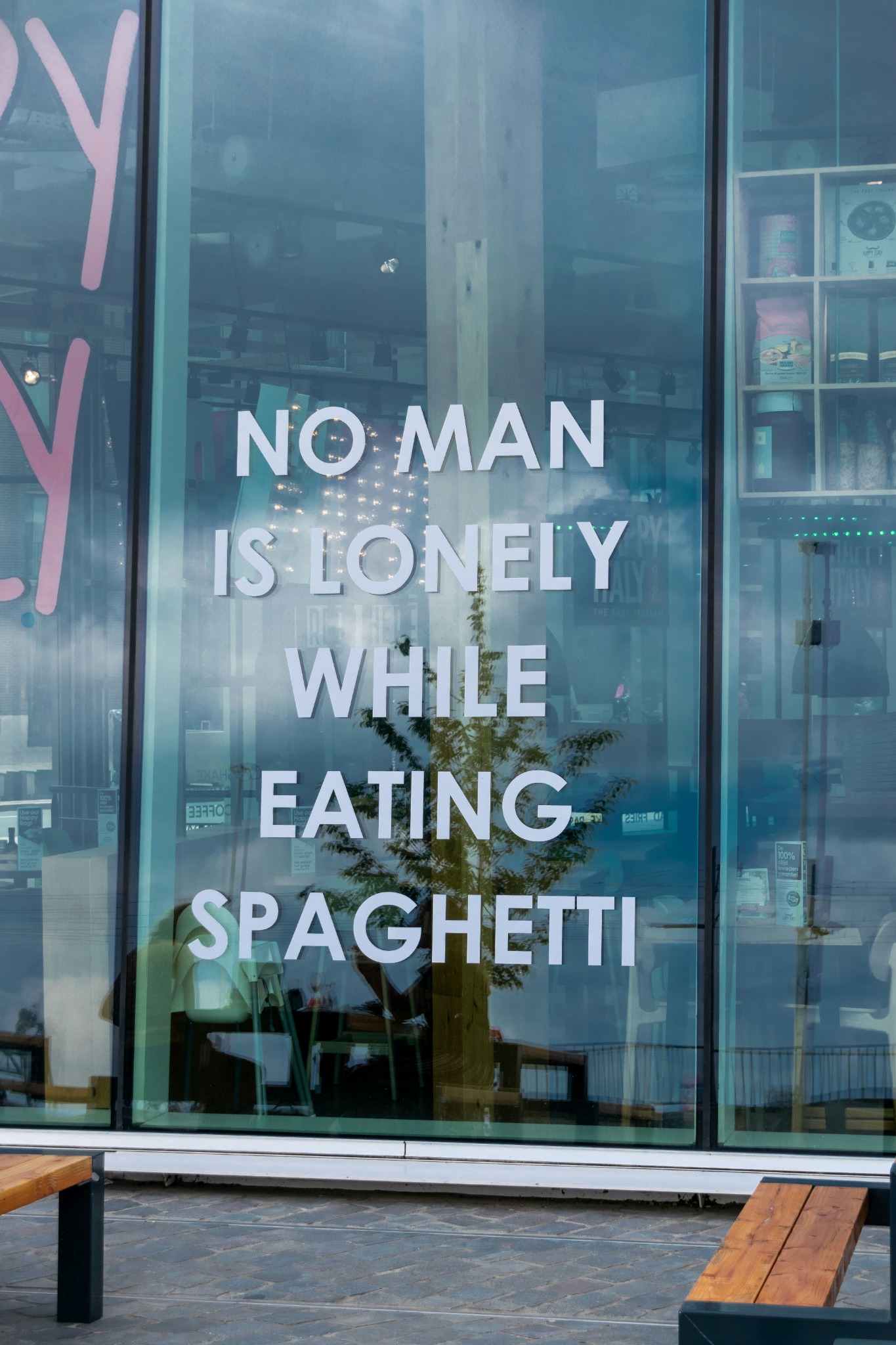 Printed window graphics on storefront glazing with oversized white typography.