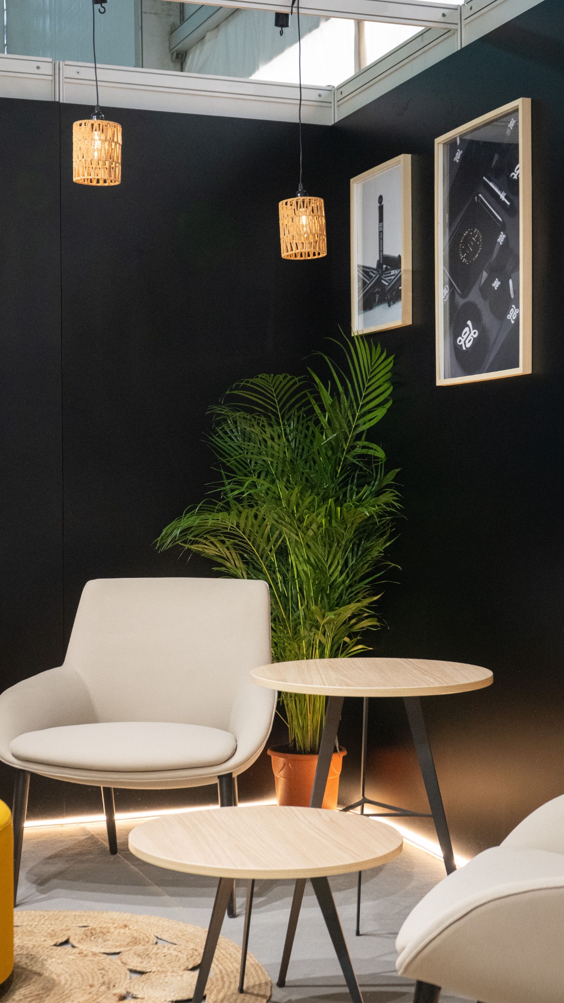 Premium exhibition booth lounge with a dark feature wall, framed graphics, seating and integrated lighting.