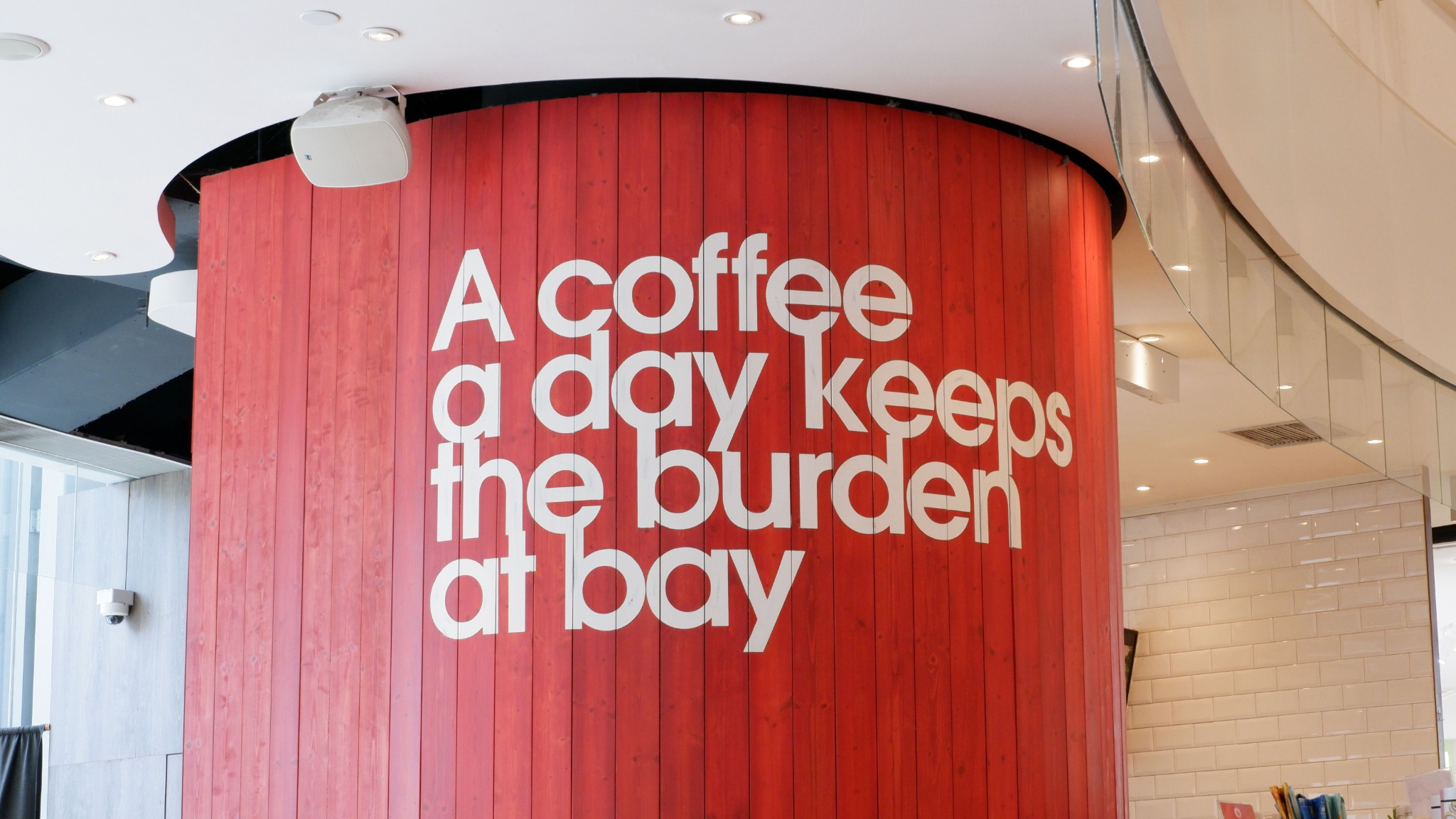 Bold branded red interior wall with large dimensional white lettering in a commercial environment