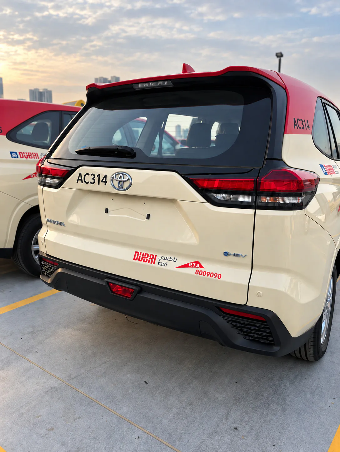 Close rear three-quarter view of a Dubai Taxi showing graphic alignment across the tailgate.