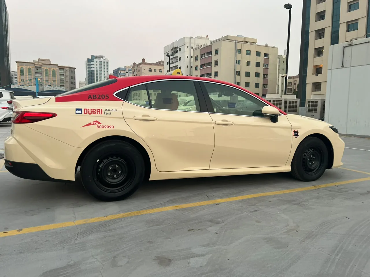Dubai Taxi Toyota Camry AB205 in Al Khatib's red and cream livery, side view.